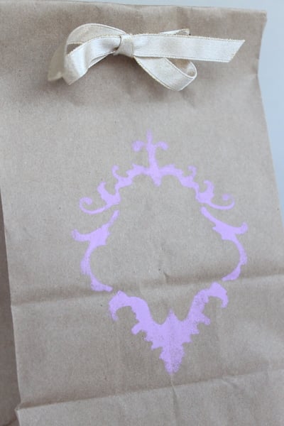 Purple design stenciled on brown bag with white ribbon