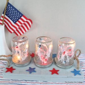 Patriotic Mason Jar Centerpiece for the Fourth of July -- make this centerpiece and light up your party in style! A fun way to add string lights to your table in mason jars! Easy to make by following this craft tutorial.