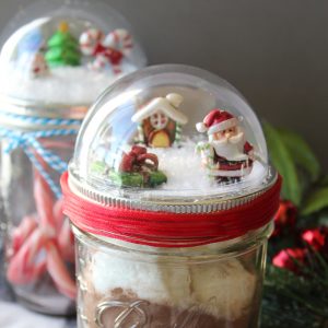 Make these mason jar Christmas gifts for those you love! Cute snow globe toppers for mason jars then add in hot chocolate or any other gift idea! #masonjars #christmas