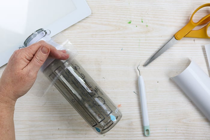 Adding markers for amount of water to drink to a water bottle with glitter vinyl and a Cricut machine.