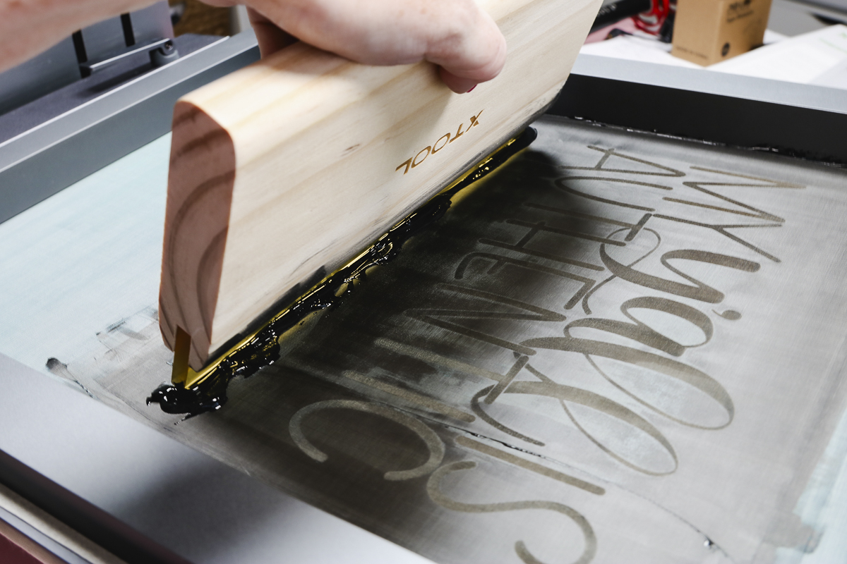 Use squeegee to pull ink across screen design.