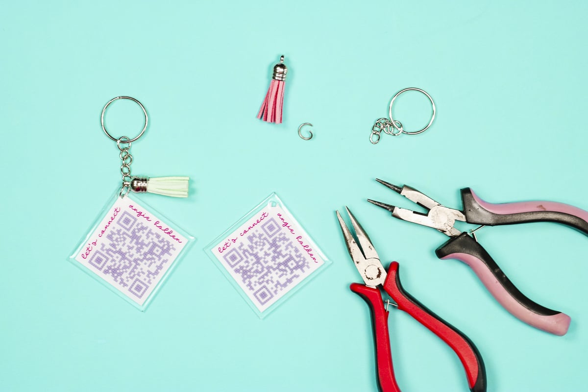 Finish QR code keychain with tassels or other findings.