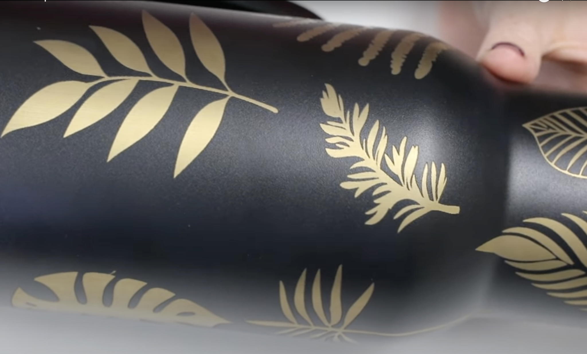 Black tumbler engraved to reveal gold designs.