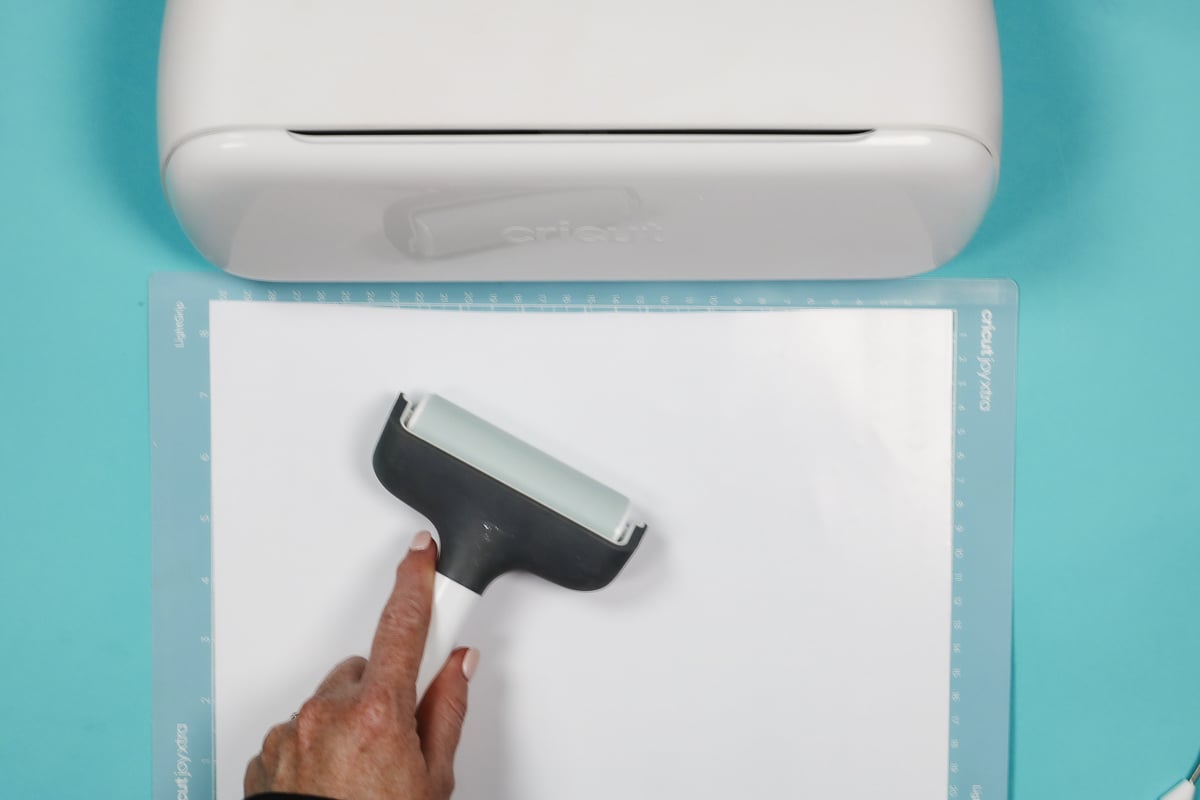 Use a brayer to smooth HTV onto mat.